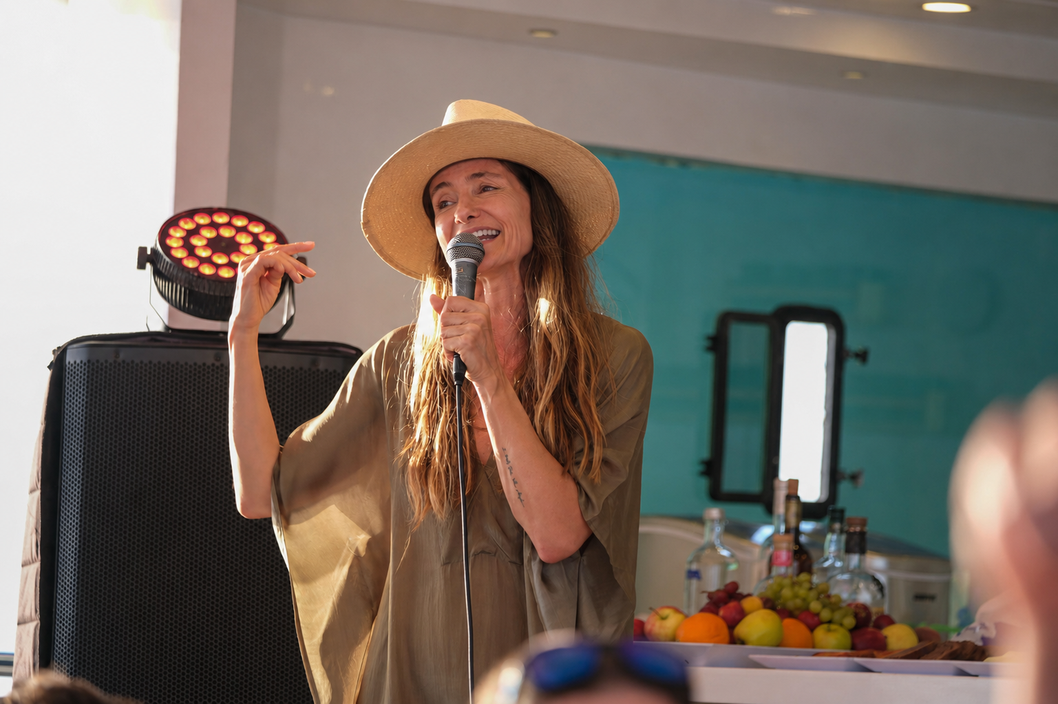 Woman in a sun hat speaking into a microphone at a gathering