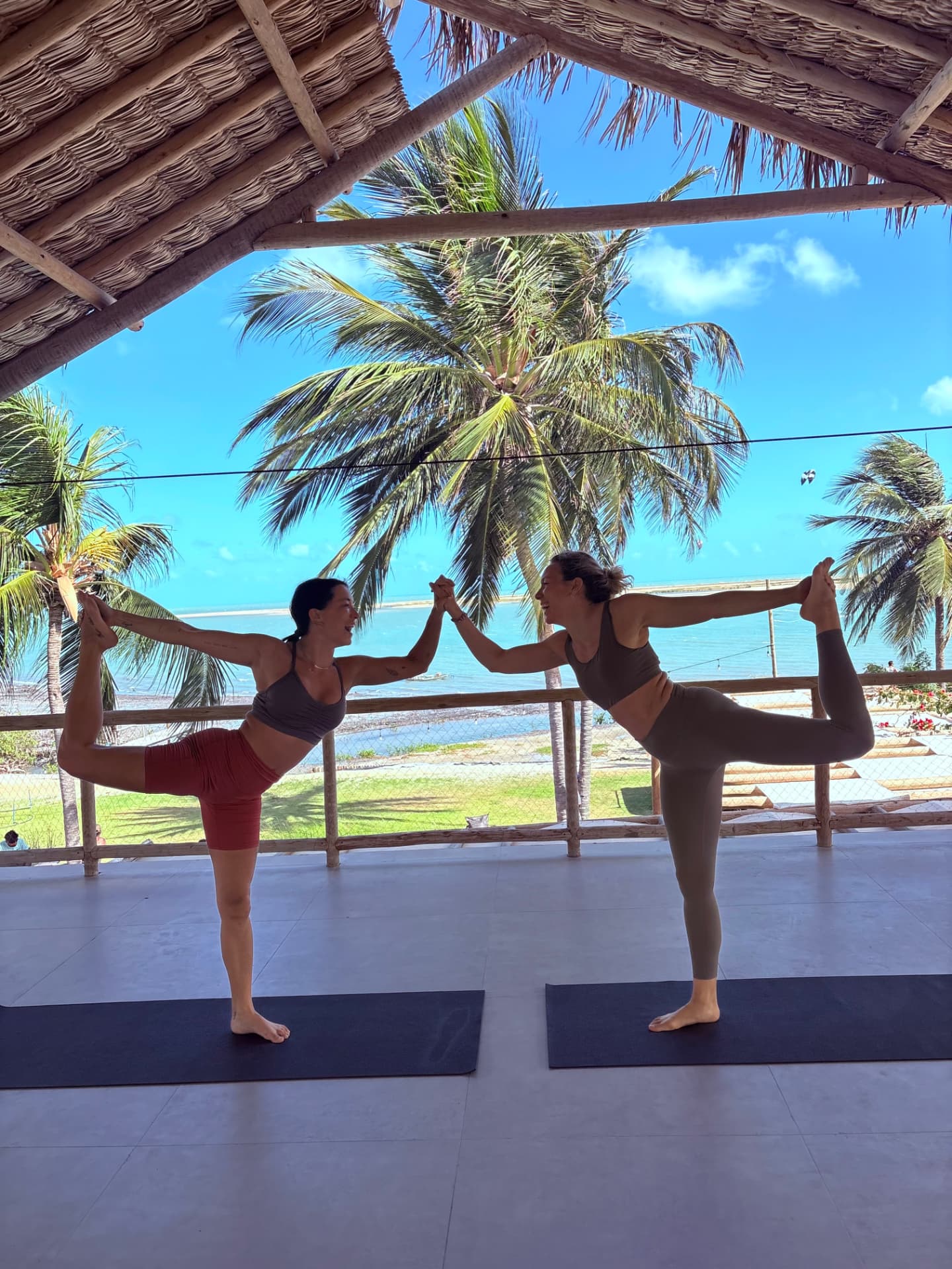Two guests balancing in dancer pose during an open-air yoga session