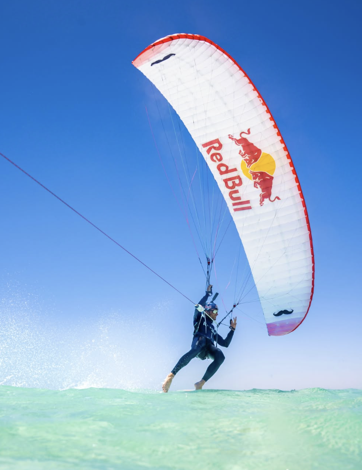 Kitesurfer flying a kite over crystal-clear turquoise water